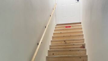 Una escala de fusta amb barana que condueix a una porta blanca al final.