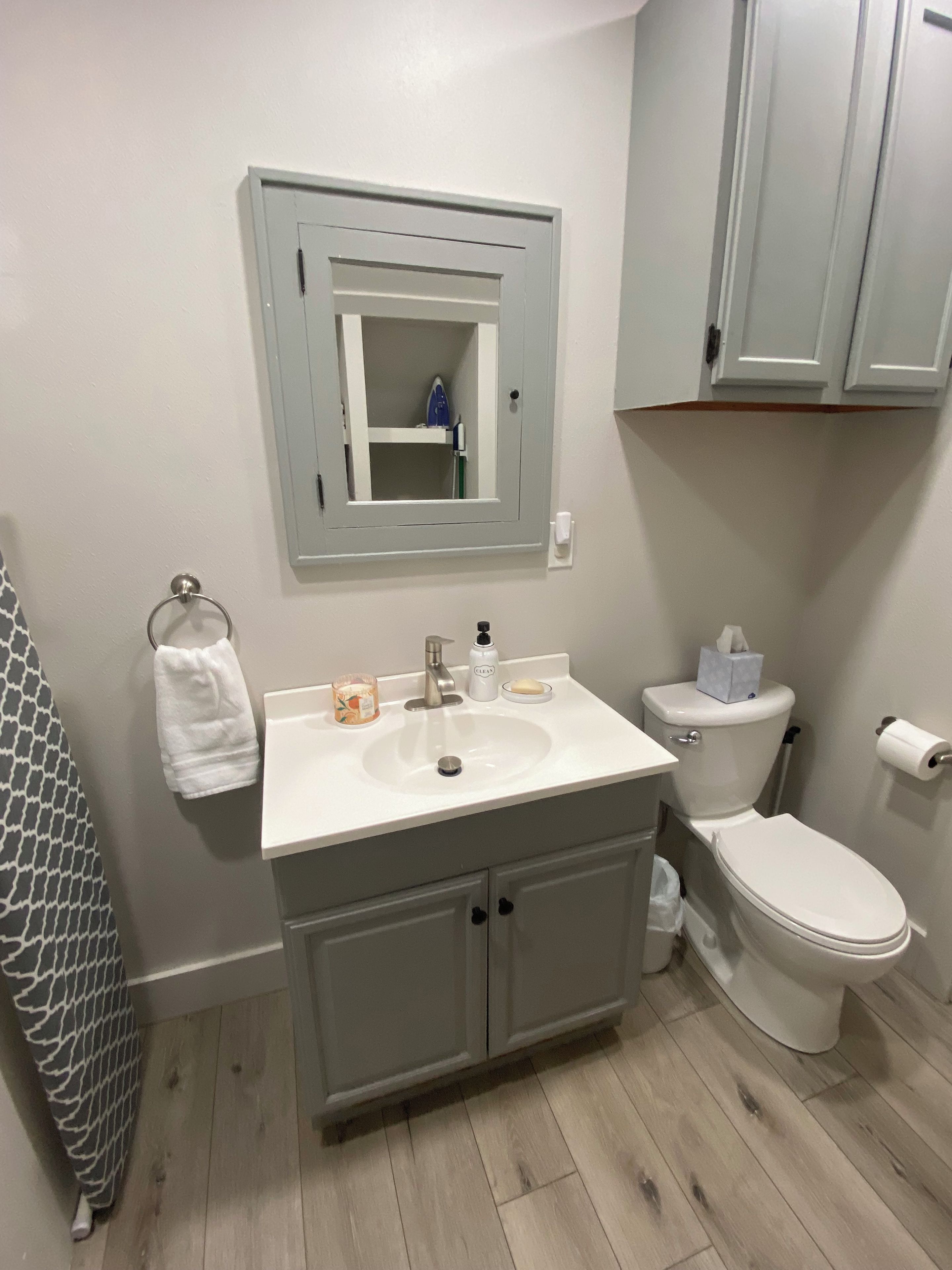 A bathroom with a white sink, a mirror, a toilet, and a towel rack.