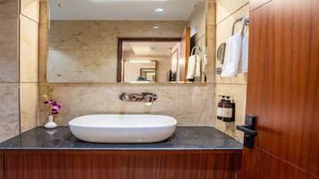A bathroom with a marble wall, a white sink, and a mirror.