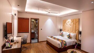 A hotel room with a bed, bedside table, mirror, and a small round table with fruit.