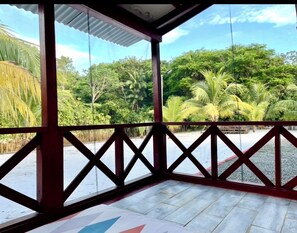 Un espace extérieur abrité offrant une vue sur une végétation luxuriante et des palmiers.