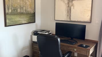Dedicated workspace with desk, monitor, and stylish art for productive stays