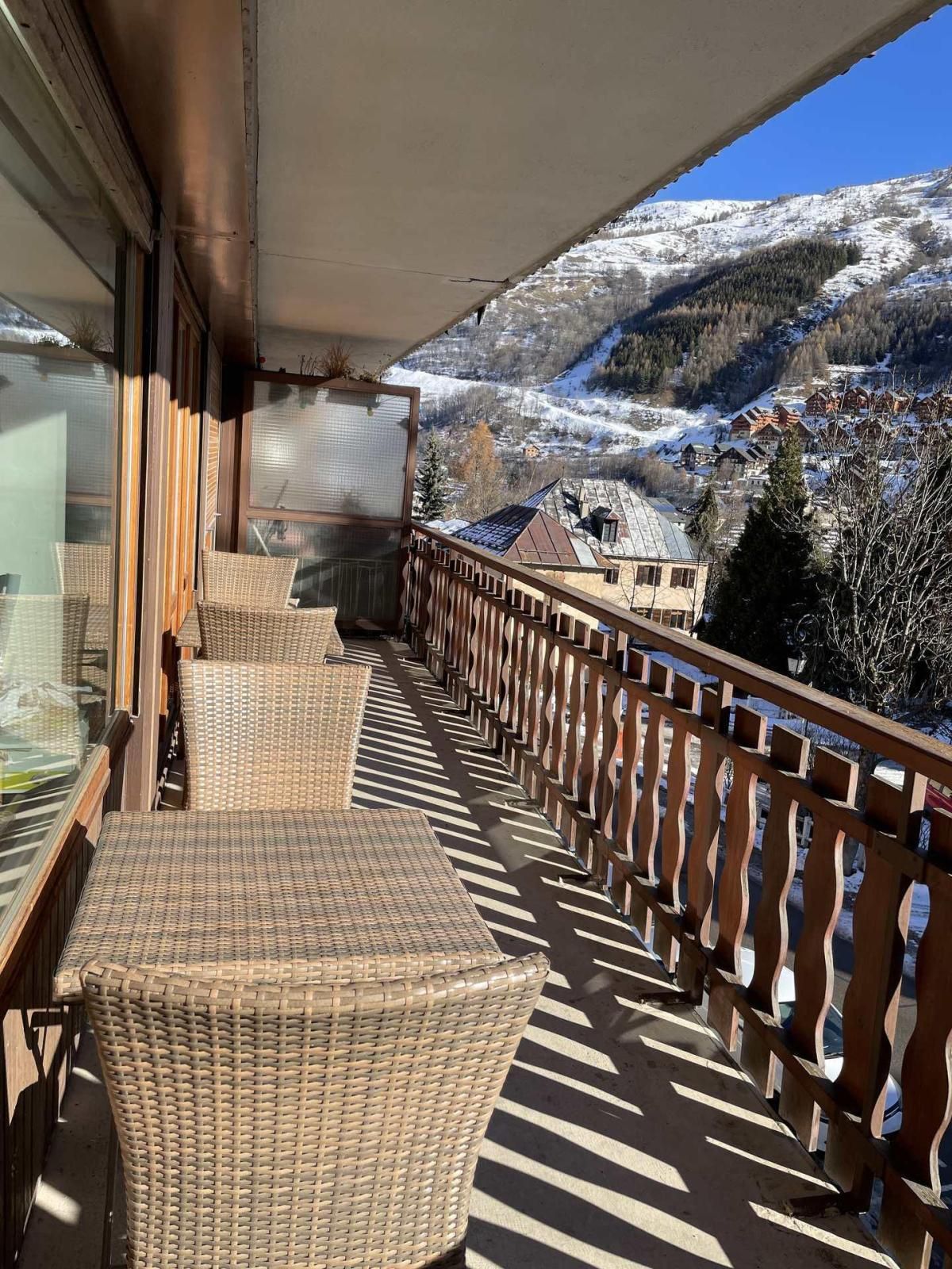 A balcony with wicker furniture and a view of a snow-covered mountain.