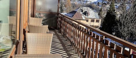 A balcony with wicker furniture and a view of a snow-covered mountain.