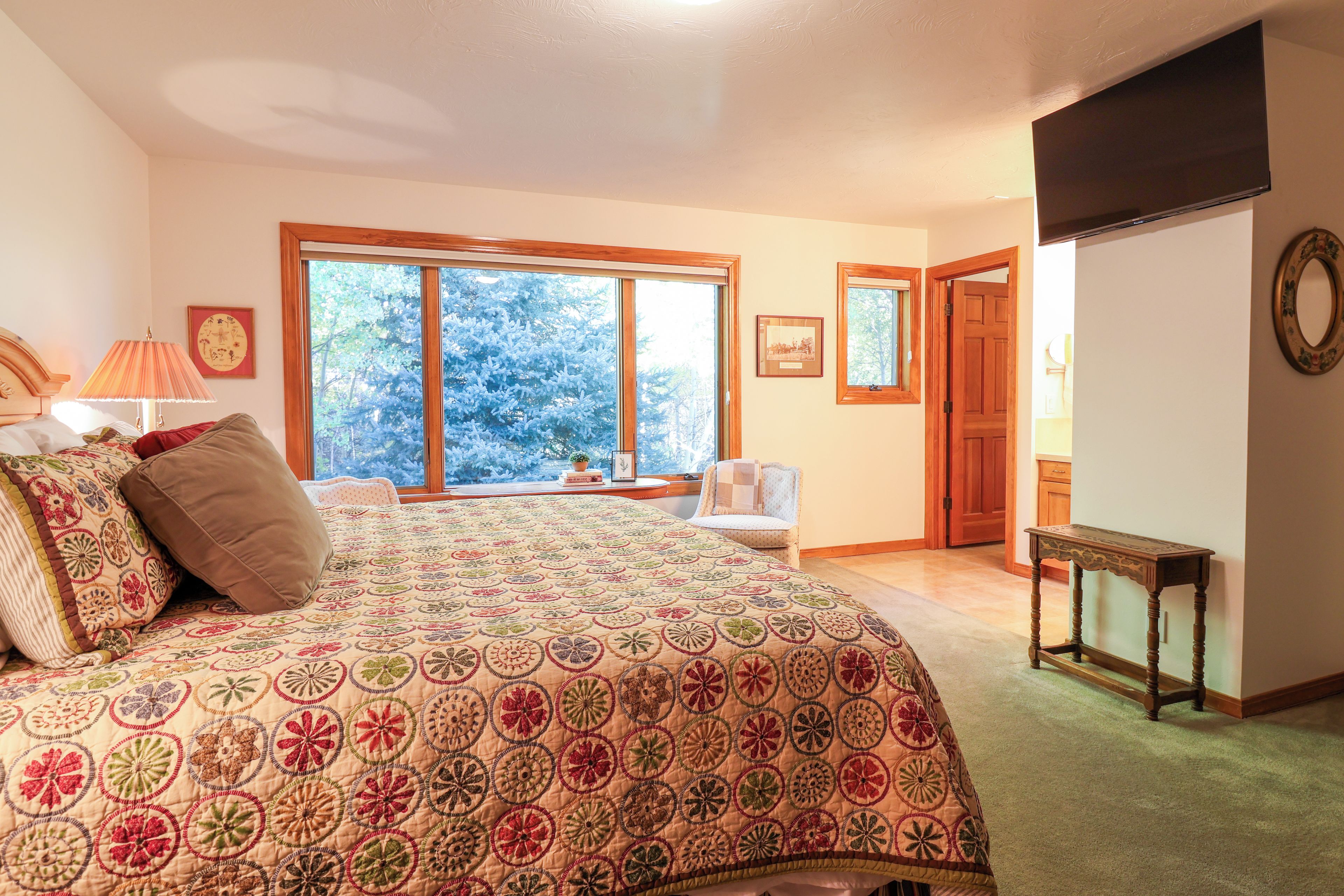 A bedroom with a large bed, a chair, a table, and a door.