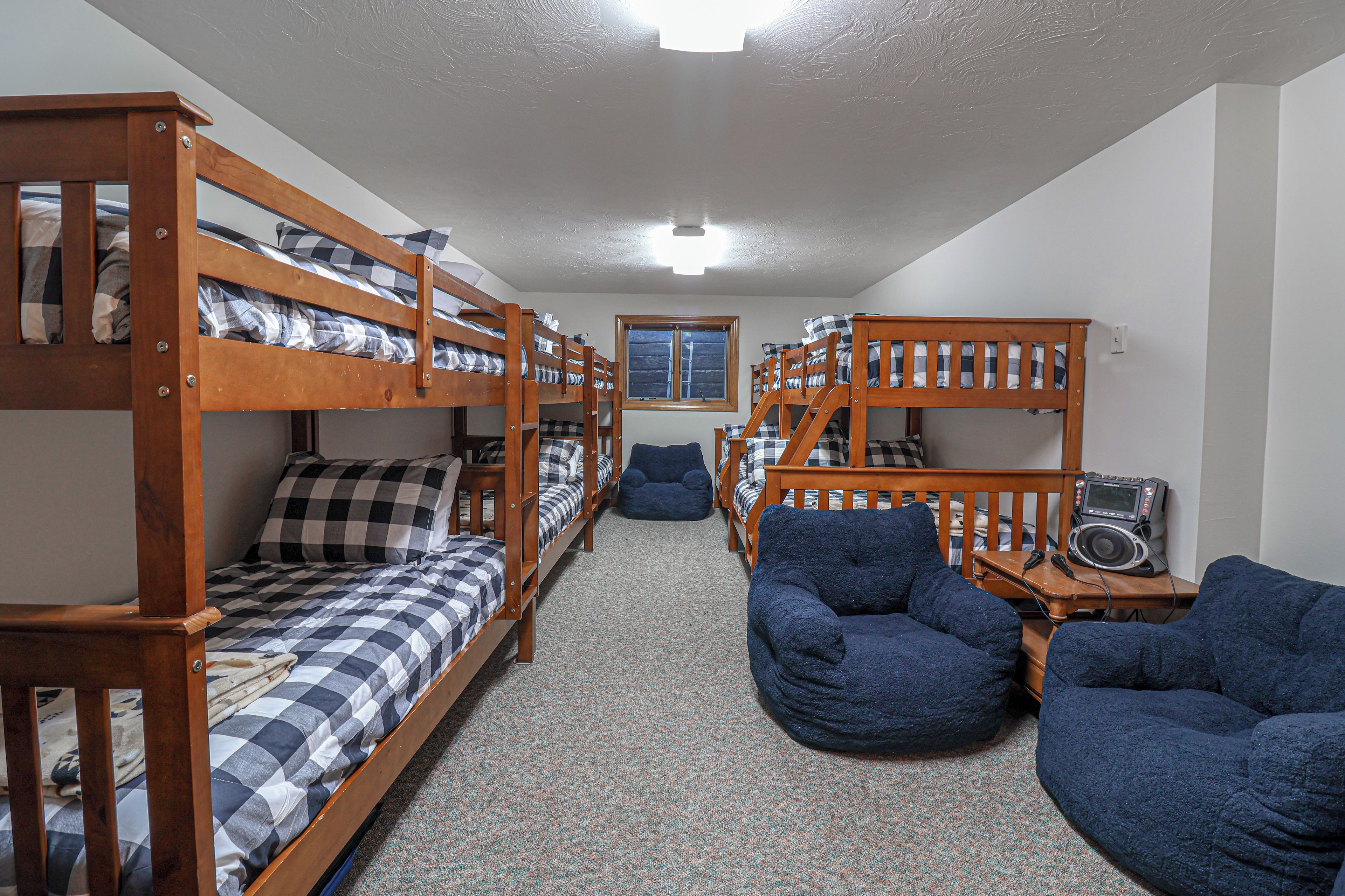 A dormitory room with bunk beds, a window, a desk with a radio, and two bean bag chairs.