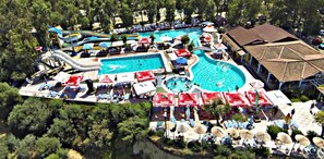 Un complejo turístico con múltiples piscinas, toboganes acuáticos y tumbonas.