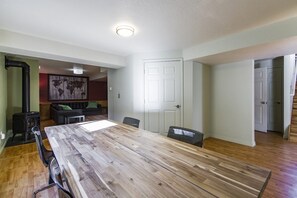 A spacious dining area with a large wooden table, surrounded by chairs, in a modern home with a fireplace and a world map artwork on the wall. - Contemporary and Blinged-Out Private Guest Suite (Greeley)