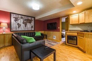 A living room with a black leather sofa, a small black coffee table, and a world map on the wall. - Contemporary and Blinged-Out Private Guest Suite (Greeley)