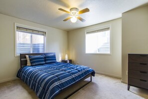 A bedroom with a bed, a nightstand, a dresser, and a ceiling fan. - Contemporary and Blinged-Out Private Guest Suite (Greeley)