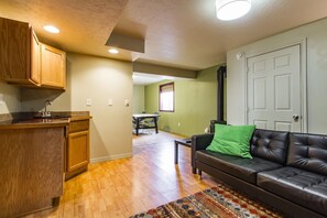 A living room with a black leather sofa, a wooden cabinet, and a patterned rug. - Contemporary and Blinged-Out Private Guest Suite (Greeley)