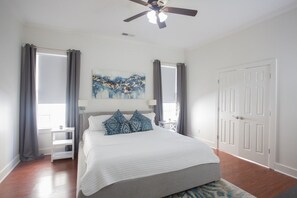 A bedroom with a bed, a ceiling fan, a painting, and a door. - Gameday Home · Dog-Friendly · Private Lake (Bessemer)
