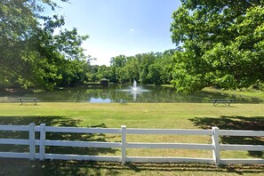 A serene park with a pond, benches, and a white fence. - Gameday Home · Dog-Friendly · Private Lake (Bessemer)