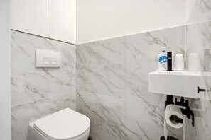 A modern bathroom with a toilet, a hand dryer, and a soap dispenser. - Spacious Family Blankenberge House (Blankenberge)