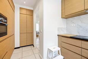 A modern kitchen with wooden cabinets, a black countertop, and a white tiled backsplash. - Spacious Family Blankenberge House (Blankenberge)