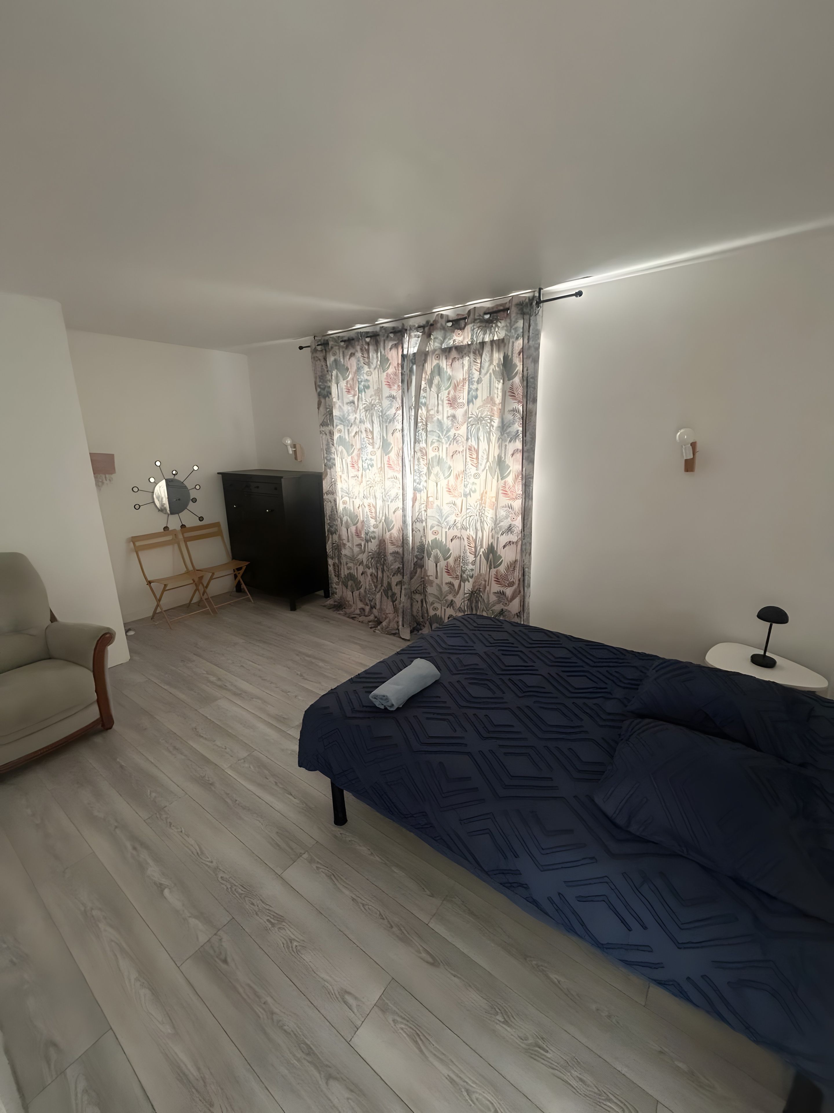 A bedroom with a bed, a chair, a desk, and curtains.