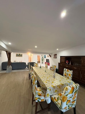Un comedor con una mesa larga, sillas y un sofá al fondo.