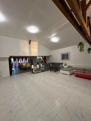 A spacious living area with a dining area, a kitchen, and a staircase. - House 'Maison 10 personnes grande terrasse grands groupes' (Parcé)