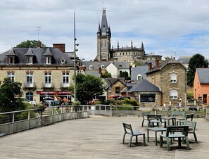 Ein Stadtplatz mit Bänken und Tischen, historischen Gebäuden und einem markanten Kirchturm.