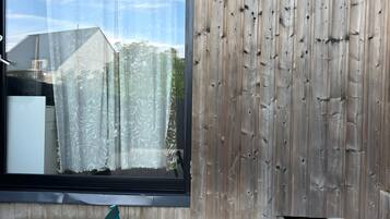 Un espace extérieur moderne, aménagé avec des sièges, un mur en bois et une grande fenêtre.