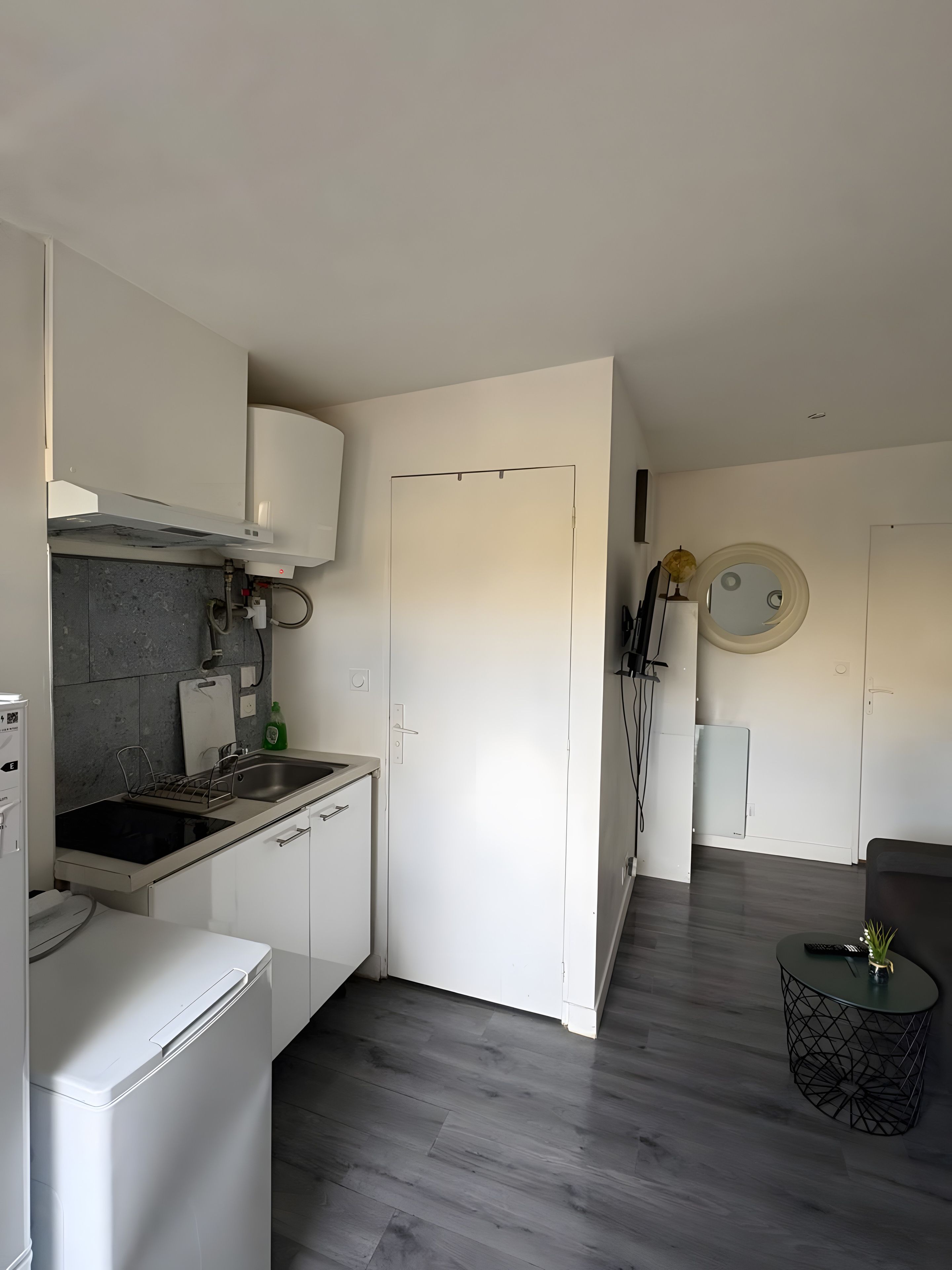 Eine moderne Küche mit eingebautem Ofen, Spüle und Herd. Es gibt eine Essecke mit rundem Tisch und einer Couch.