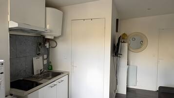 Eine moderne Küche mit eingebautem Ofen, Spüle und Herd. Es gibt eine Essecke mit rundem Tisch und einer Couch.