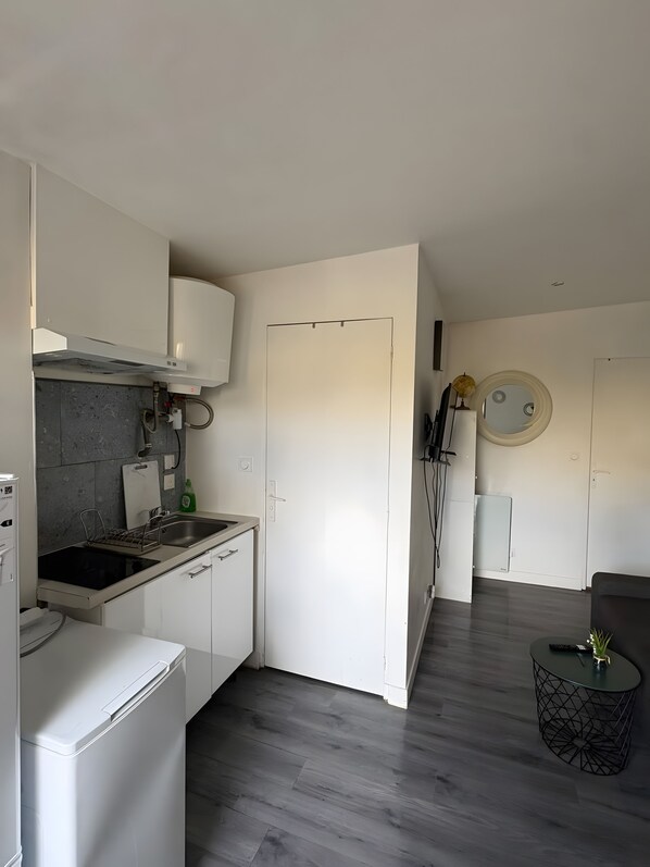 Et moderne køkken med indbygget ovn, vask og komfur. Der er et spiseområde med et rundt bord og en sofa.