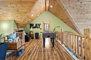 Ein Loft-Zimmer mit Holzbalkendecke, einem Kicker, einem Globus und einer Dartscheibe.