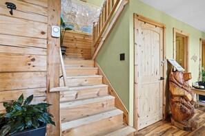 Eine Holztreppe mit Handlauf, einem an der Wand befestigten Lichtschalter und einer Holztür mit Schloss.