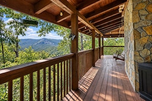 A wooden deck with a stone wall, overlooking a mountainous landscape. - Wildcat Cabin at Lake Lure (Lake Lure)