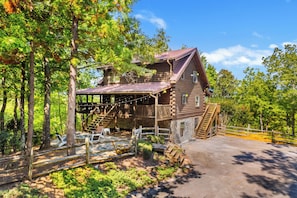 A rustic log cabin with a porch, stone foundation, and a wooden fence. - Wildcat Cabin at Lake Lure (Lake Lure)