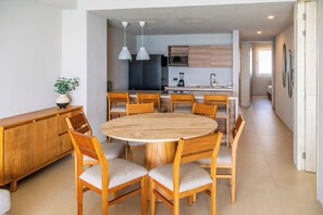 Una cocina moderna con una isla central, sillas de madera e iluminación colgante.