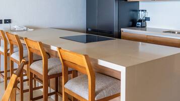 Une cuisine moderne avec un îlot central, des chaises en bois, un réfrigérateur noir et un four à micro-ondes.