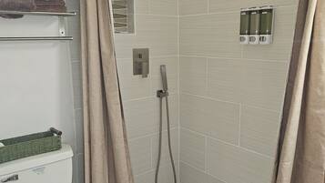 A bathroom with a shower, toilet, and towel rack.