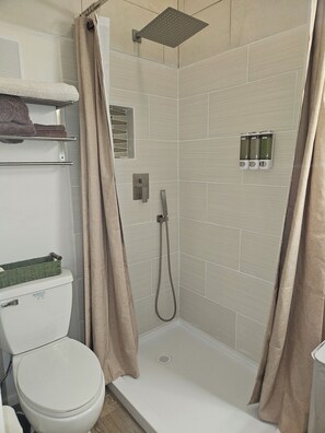 Un bagno con doccia, WC e portasciugamani.