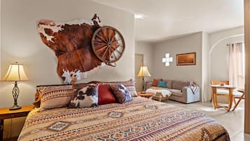 A spacious bedroom with a large bed, a wall-mounted wooden wheel, a sofa, and a small table.