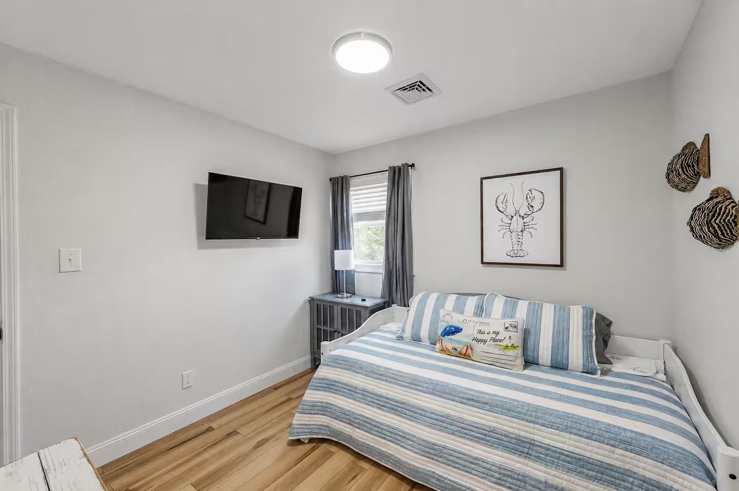 A bedroom with a bed, a TV, a radiator, and a window with curtains.