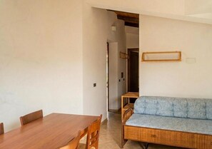 A room with a wooden dining table, a blue sofa, and a small wooden table. - Apartment With Shared Pool Near the sea (Nicotera)