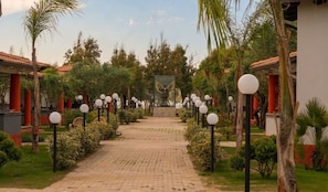 A pathway leading to a building with a central statue, flanked by palm trees and lamp posts. - Apartment With Shared Pool Near the sea (Nicotera)