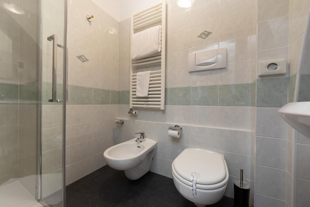 Een badkamer met een douchecabine van glas, een bidet en een toilet.