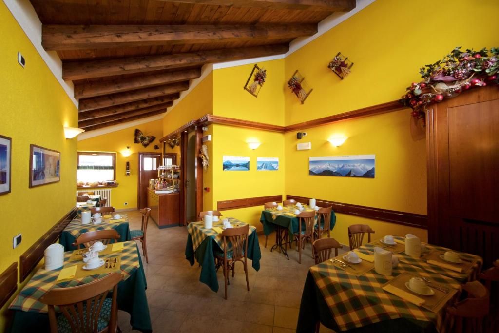 A dining area with tables set for service, wooden beams on the ceiling, and framed pictures on the walls.