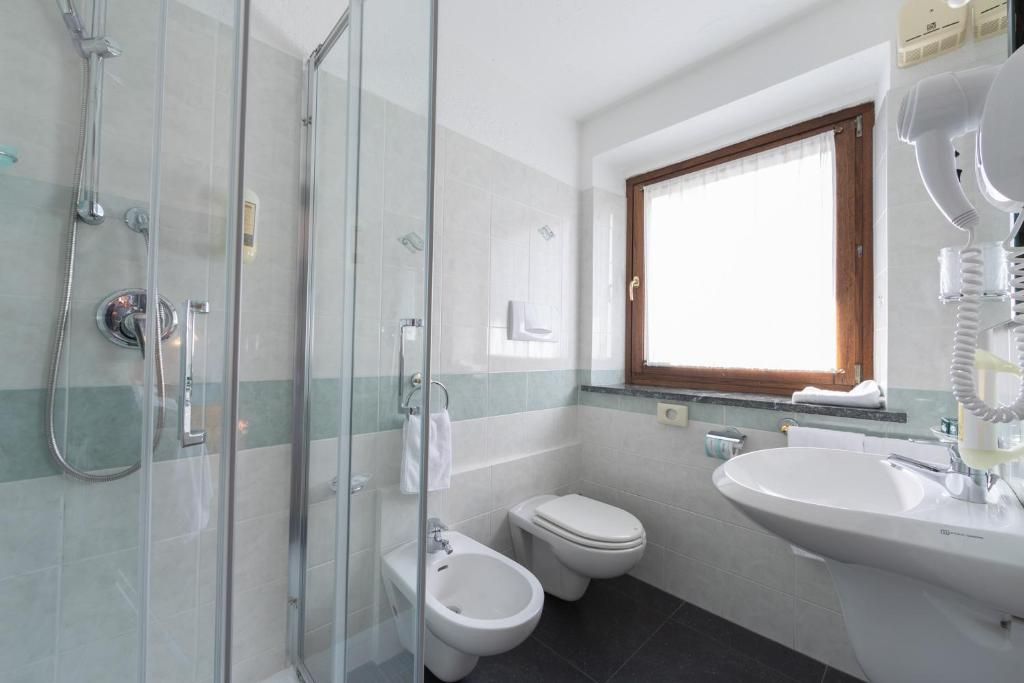 A bathroom with a glass shower enclosure, a toilet, and a sink.