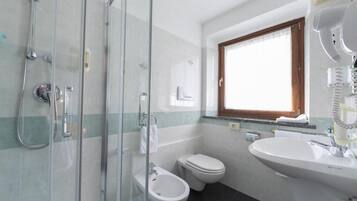A bathroom with a glass shower enclosure, a toilet, and a sink.