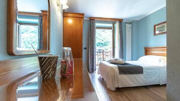 A hotel room with a bed, a wooden desk, a window, and a view of the outdoors.