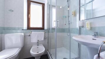 Ein Badezimmer mit Toilette, Bidet, einer Duschkabine und einem Waschbecken.