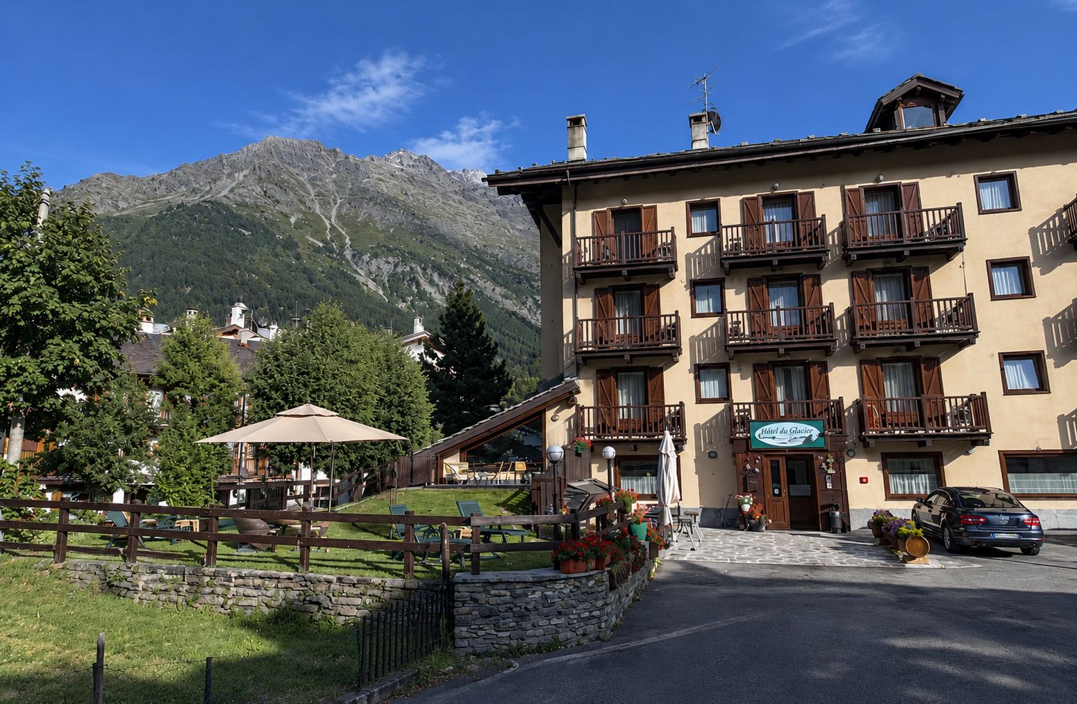Ein Hotel mit mehreren Balkonen, einer Steinwand und einer Bergkulisse.