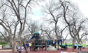Ein Spielplatz mit verschiedenen Spielgeräten, darunter eine Rutsche, Klettergerüste und Schaukeln.
