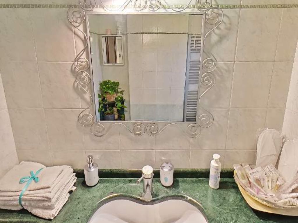 A bathroom with a vanity, a sink, and a mirror. There are towels stacked on the side and toiletries on the counter.