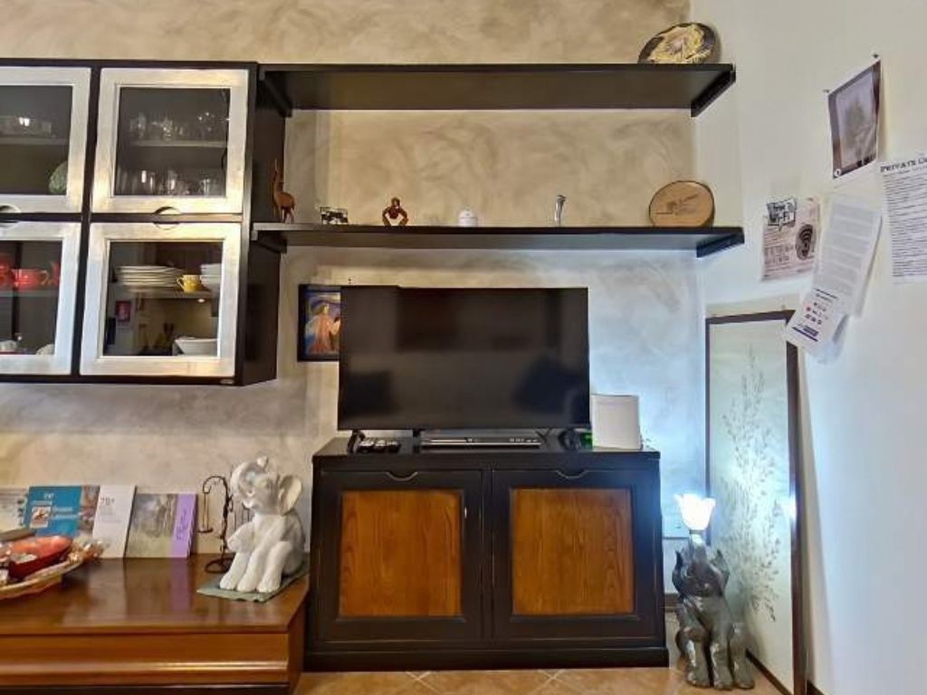 Una cucina con forno a incasso, frigorifero e microonde. Ci sono pensili sopra il bancone e una piccola mensola con oggetti decorativi.