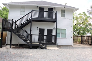 A two-story building with a black staircase and railing, a front porch, and a driveway. - East Downtown Loft + Gated Parking (Houston)